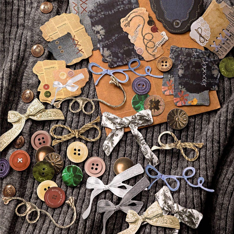 May include: An assortment of craft supplies including colorful buttons, decorative bows, and small paper tags with denim and newspaper-like textures. The items are arranged on a gray knit fabric background, creating a vintage aesthetic.