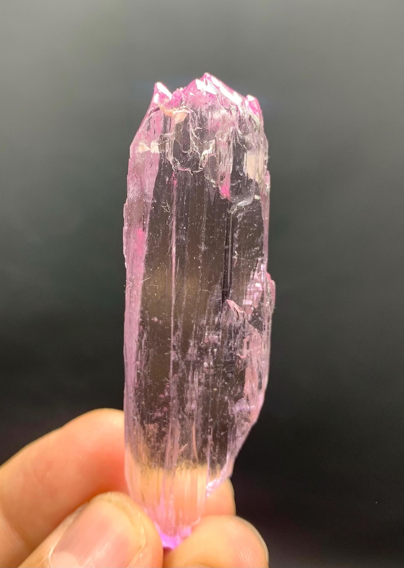 Pu&ograve; includere: Un cristallo rosa traslucido con una punta appuntita e una superficie liscia e lucida.