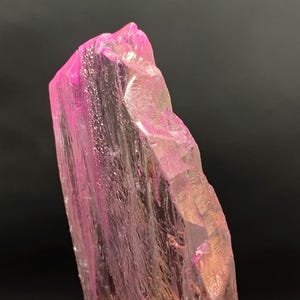 Pu&ograve; includere: Un grande cristallo rosa traslucido con una superficie ruvida e sfaccettata. Il cristallo &egrave; allungato e ha una punta appuntita.