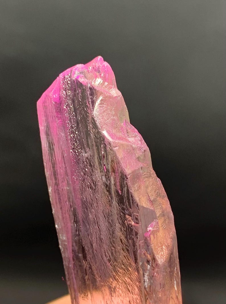 Pu&ograve; includere: Un grande cristallo rosa traslucido con una superficie ruvida e sfaccettata. Il cristallo &egrave; allungato e ha una punta appuntita.