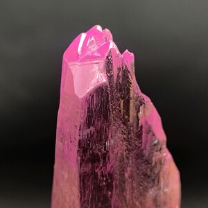 Pu&ograve; includere: Primo piano di un cristallo rosa con una punta appuntita. Il cristallo ha una superficie liscia e lucida ed &egrave; traslucido.
