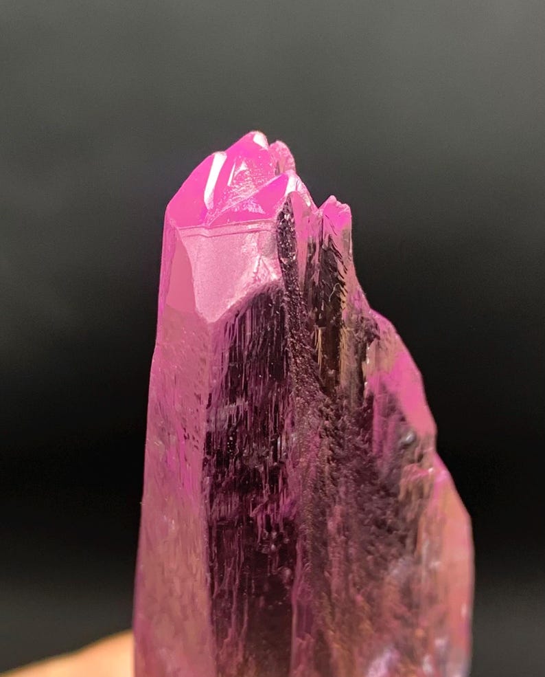 Pu&ograve; includere: Primo piano di un cristallo rosa con una punta appuntita. Il cristallo ha una superficie liscia e lucida ed &egrave; traslucido.