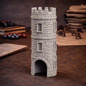 Puede incluir: Una torre de castillo en miniatura cilíndrica gris con un diseño de ladrillo de piedra. La torre tiene puertas arqueadas, ventanas rectangulares y una parte superior almenada. Accesorio de juego de mesa.