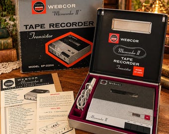 Può includere: Un registratore a nastro a transistor vintage Webcor Microcorder II, modello EP-2204, presentato nella sua scatola originale con custodia, manuale di istruzioni e fogli informativi, caratterizzato da una finitura metallica argento e nera.