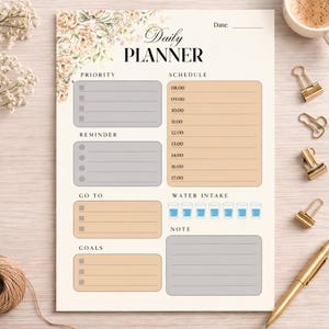 May include: A beige daily planner with floral accents and the words "Daily Planner" at the top. It includes sections for priority, schedule, reminders, goals, and water intake. Gold binder clips and a pen are on the side.