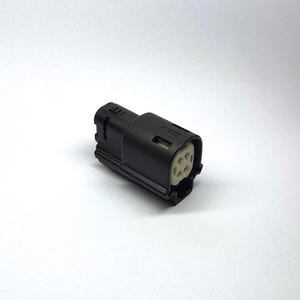 Può includere: Un connettore elettrico nero con un corpo rettangolare e un interno bianco. Il connettore ha più prese per perni ed è progettato per collegamenti elettrici sicuri. L'immagine è su sfondo bianco.