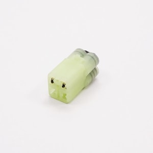 Puede incluir: Un conector eléctrico verde con dos pines dorados.