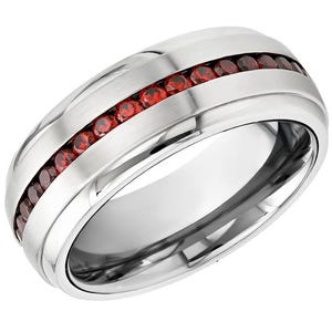 May include: A silver-colored ring with a row of small, round, red gemstones set into a channel. The ring has a polished, reflective surface and a simple, elegant design. The gemstones are evenly spaced and add a pop of color.