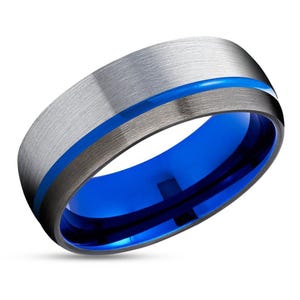 May include: A silver and black tungsten carbide ring with a blue inlay. The ring has a brushed finish and a beveled edge.