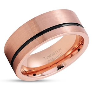 May include: A rose gold tungsten carbide ring with a black inlay. The ring is engraved with "TUNGSTEN CARBIDE".