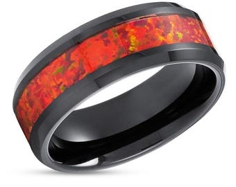 May include: A black ring with a vibrant red and orange inlay. The ring's band is a glossy black, and the inlay features a mosaic of fiery colors. This piece of jewelry is a bold statement accessory.