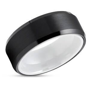 May include: A black tungsten carbide ring with a brushed finish and a white ceramic inlay.