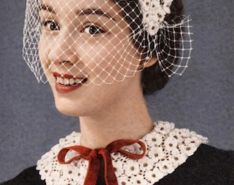 May include: A white crocheted headpiece featuring a delicate netting veil that covers the upper face, paired with a matching white crocheted collar adorned with a dark red velvet ribbon tie, worn over a black button-down garment.