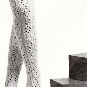May include: A pair of cream-coloured, knee-high knitted socks with a delicate openwork pattern. The socks feature vertical ribbing and a decorative diamond-shaped openwork design. The image is in black and white.