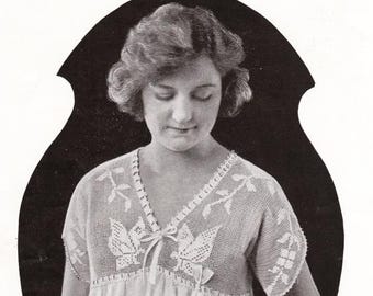 May include: A vintage black and white image of a woman wearing a light-colored, open-weave top with a V-neckline. The top features intricate white floral and leaf patterns, with a bow at the neckline. The woman has short, curly hair.