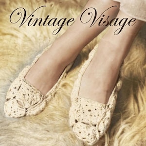 Puede incluir: Zapatillas de ganchillo de color crema con un diseño calado. Las zapatillas se muestran sobre una superficie suave y texturizada. El texto "Vintage Visage" se muestra en una elegante escritura en la parte superior de la imagen.