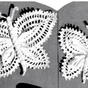 May include: Two white, crocheted butterfly decorations. The butterflies have detailed wing patterns and antennae. The wings are open, and the butterflies appear to be handmade. The background is a neutral gray.