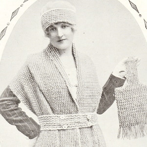 May include: A vintage black and white image of a woman wearing a knitted outfit. The outfit includes a hat, shawl, belted coat, and a small handbag with fringe. The woman is wearing a white glove on her left hand.