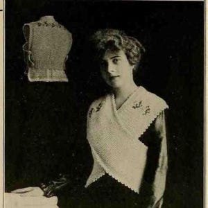 May include: A vintage black and white photograph featuring a woman wearing a white knitted wrap with floral embroidery. A matching knitted vest is displayed in the background. The woman is looking at the camera.