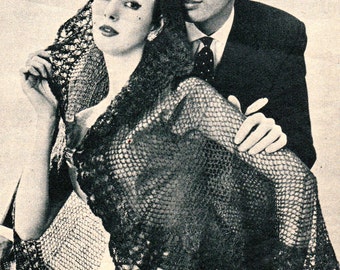 May include: A black lace shawl draped over a woman's shoulders. She is standing next to a man in a suit and tie. The couple is looking at each other.