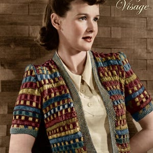 May include: A woman wearing a vintage-style, short-sleeved cardigan. The cardigan features a colorful geometric pattern in red, blue, and yellow. The text "Vintage Visage" is in the upper right corner. The woman is wearing a light-colored collared shirt.