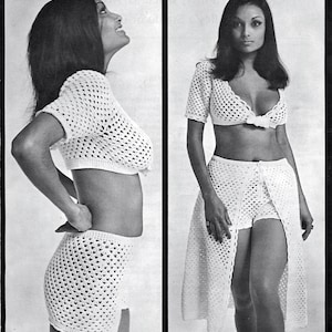 May include: A two-piece white crochet outfit. The top is a short-sleeved crop top. The bottom is a skirt with a slit. The outfit is made of a open weave crochet pattern.
