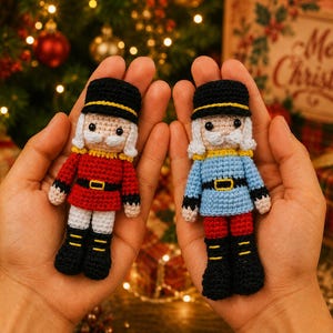 May include: Two small crocheted nutcracker dolls, one wearing a red jacket and the other a light blue jacket. Both dolls feature black hats with yellow trim, white hair, black boots with yellow accents, and black belts with yellow buckles.