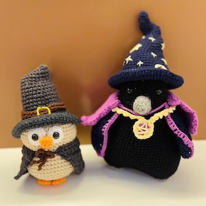 Puede incluir: Dos búhos de peluche tejidos a crochet, uno lleva una túnica y un sombrero de mago morado y negro con estrellas, el otro lleva un sombrero marrón con una hebilla y una capa marrón.