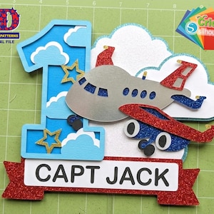 Könnte beinhalten: Ein mehrschichtiges Papierdesign mit einer blauen Eins mit Wolken und goldenen Sternen. Ein silbernes Flugzeug mit roten und blauen Akzenten befindet sich über einem Banner mit der Aufschrift "CAPT JACK". Das Design enthält den Text "SVG PATTERNS DIGITAL FILE".