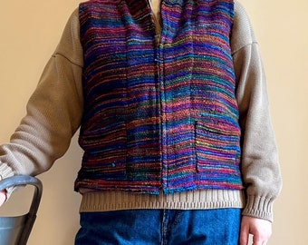 May include: A multi-colored striped vest with a zipper closure and two pockets. The vest is made of a woven fabric and has a casual style.