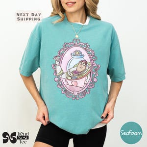 a woman wearing a green shirt with a picture of a mermaid on it