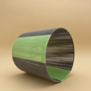 May include: A gray and green cylindrical woven basket with a striped pattern.