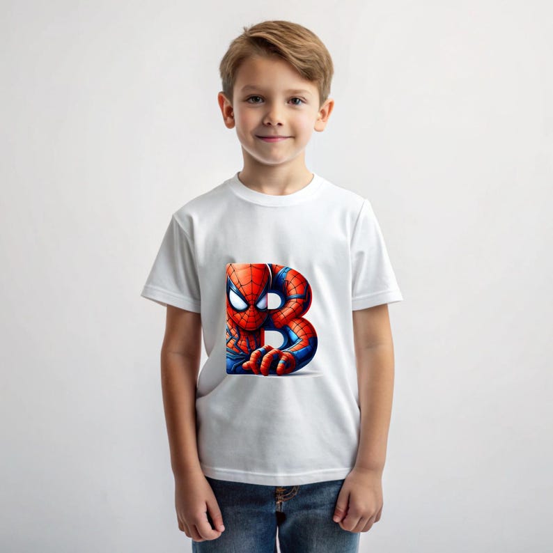 Pu&ograve; includere: Una maglietta bianca con una grafica di Spiderman rossa e blu sul davanti. La grafica mostra Spiderman che sbircia da dietro la lettera "B".