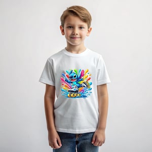 May include: White t-shirt featuring a blue cartoon character on roller skates, surrounded by colourful paint splatters.