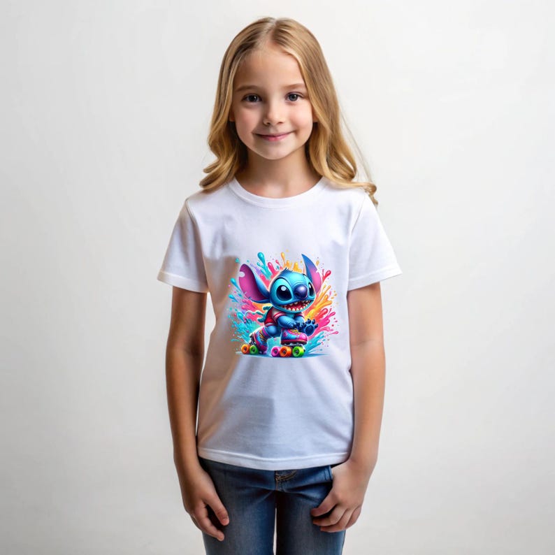 May include: White t-shirt featuring a blue cartoon character on roller skates. The character is surrounded by colourful paint splatters.