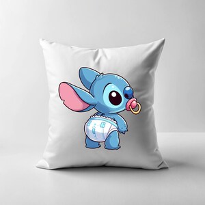 May include: A white cushion featuring a blue and pink cartoon character wearing a nappy and a dummy. The character has large eyes and a stitched appearance.