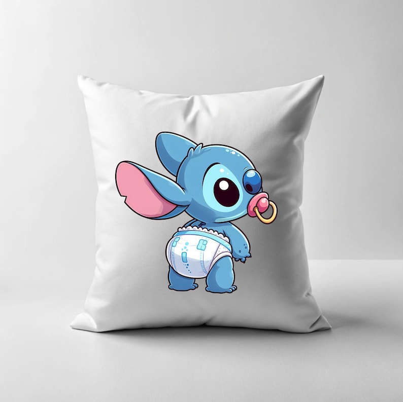 May include: A white cushion featuring a blue and pink cartoon character wearing a nappy and a dummy. The character has large eyes and a stitched appearance.