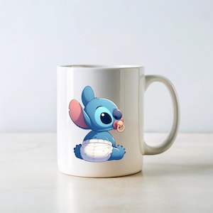 May include: White ceramic mug featuring a blue cartoon character wearing a nappy and a dummy. The character is Stitch from the Disney film Lilo & Stitch.
