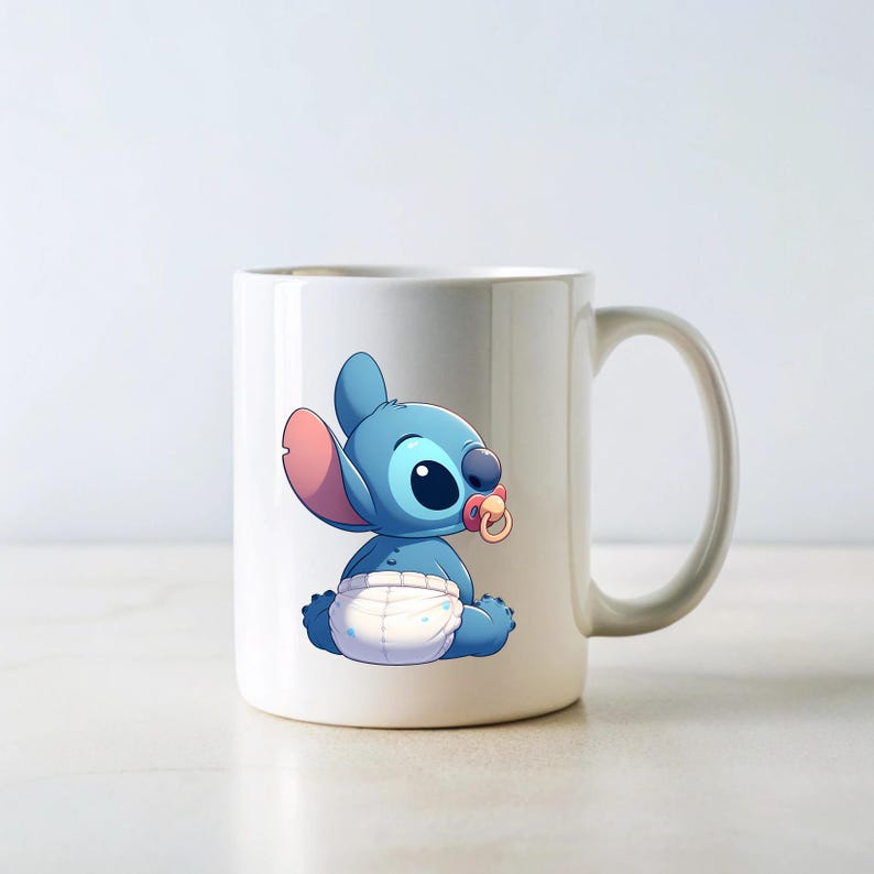 May include: White ceramic mug featuring a blue cartoon character wearing a nappy and a dummy. The character is Stitch from the Disney film Lilo & Stitch.