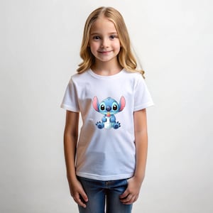 以下が含まれることがあります： 白いTシャツには、青い宇宙人キャラクターであるスティッチが哺乳瓶を持っている漫画のイラストが描かれています。 このTシャツは、金髪の女の子と青いジーンズが着用しています。