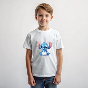 May include: A white t-shirt featuring a blue cartoon character wearing a nappy and a dummy. The character has large blue eyes and pink ears.