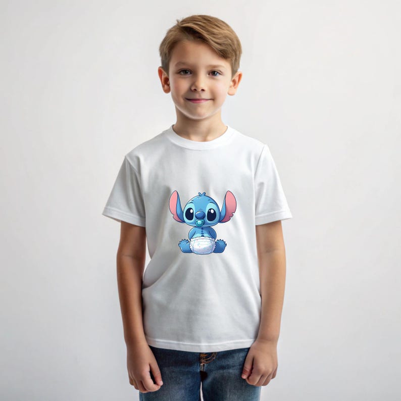 May include: A white t-shirt featuring a blue cartoon character wearing a nappy and a dummy. The character has large blue eyes and pink ears.