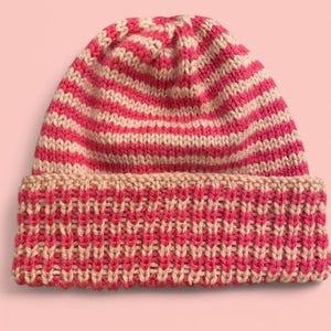 May include: A pink and beige striped knitted beanie with a folded cuff. The beanie is made of a soft, warm yarn and has a classic design.