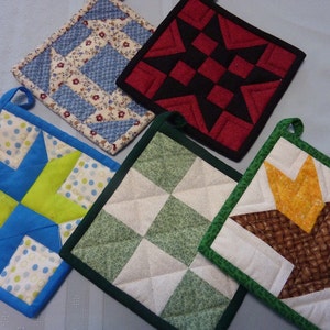 May include: Four colorful quilted pot holders with different patterns. The pot holders are square and have a loop for hanging. The patterns include a blue and green star, a red and black star, a green and white checkered pattern, and a brown and white pattern.