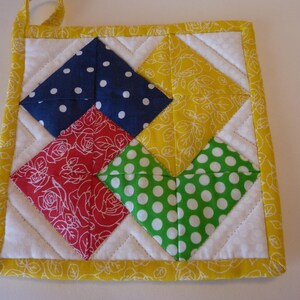 May include: A yellow, red, blue, and green patchwork pot holder with a white background. The pot holder is made of fabric squares with different patterns, including polka dots, floral designs, and solid colors.