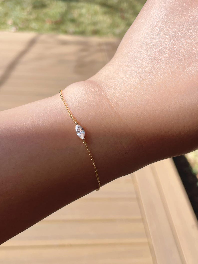 Pu&ograve; includere: Un delicato braccialetto d'oro con un diamante taglio marquise. Il diamante &egrave; il punto focale, incastonato in un design semplice ed elegante. Il braccialetto &egrave; indossato su un polso, mettendo in risalto la sua sottile brillantezza e la sua estetica raffinata.