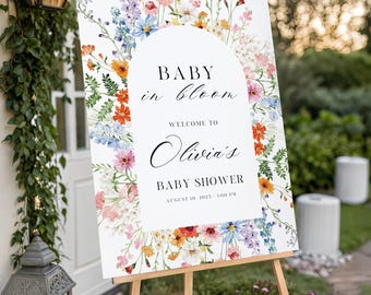 Puede incluir: Un letrero de bienvenida rectangular para baby shower con fondo blanco, un arco central y flores silvestres en acuarela de colores. El texto dice: BABY in bloom, WELCOME TO Olivia's BABY SHOWER, AUGUST 10, 2025 - 3:00 PM.
