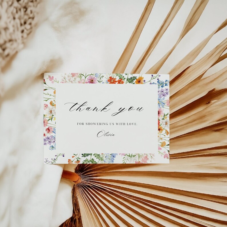 May include: A floral thank you card with the words "Thank you" in elegant script. The card is bordered with a colorful floral pattern and includes the text "For showering us with love" and the name "Olivia".