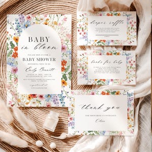 May include: A set of baby shower stationery with a floral design. The invitation features the text "Baby in Bloom" and event details. Additional cards include "Diaper Raffle," "Books for Baby," and a thank you note. The stationery is decorated with colorful flowers.