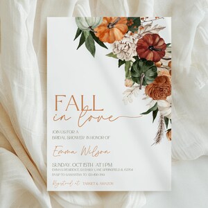 May include: A white invitation card with the text "FALL in love" in a copper color. The card is decorated with watercolor pumpkins, flowers, and greenery. The invitation is for a bridal shower honoring Emma Wilson.